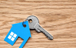 A key and a keyring in the shape of a blue house.